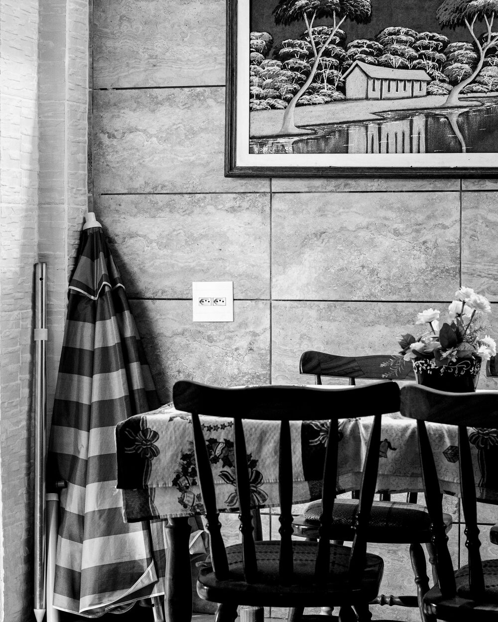 Dining room with a detailed grey toile wallpaper, black chairs and framed artwork