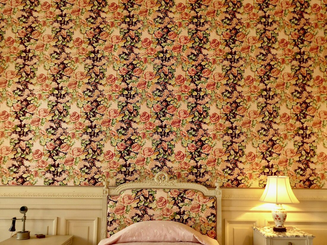 Bedroom with a warm vintage floral damask wallpaper and matching bedside table lamps