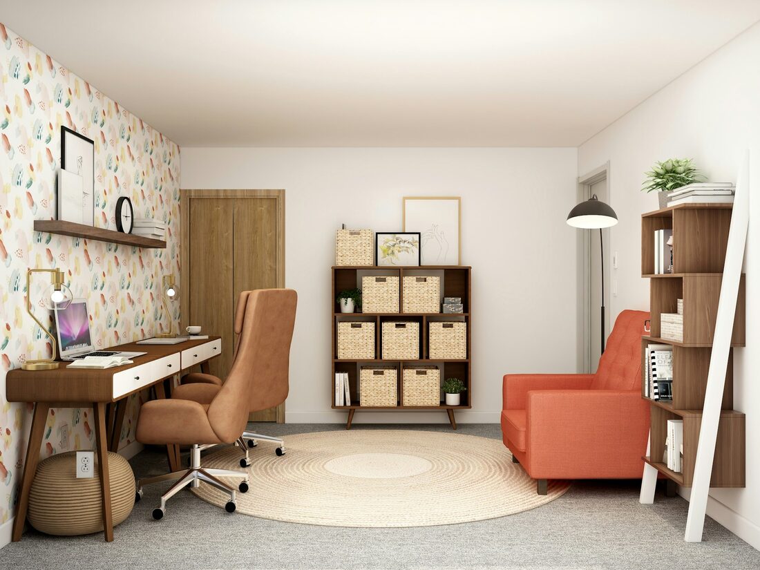 Home office with a light botanical patterned wallpaper, a wood desk and an orange accent chair