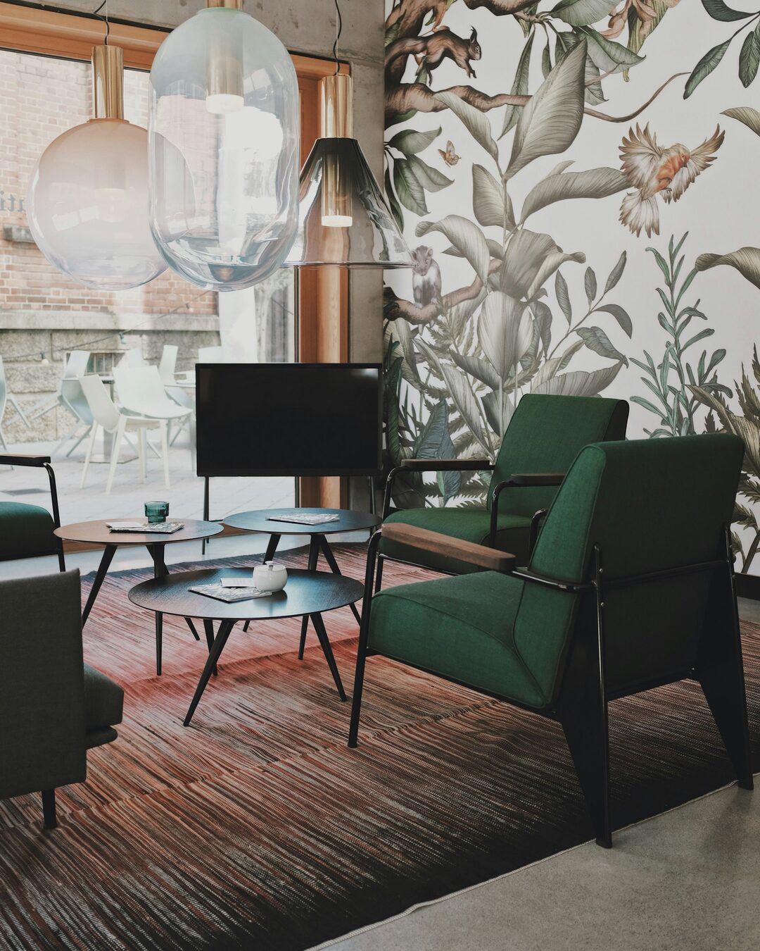 Living room with a botanical patterned wallpaper feature wall, a green accent armchair and hanging pendant lights